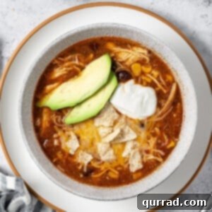 overhead bowl of chicken taco soup with sliced avocado and sour cream