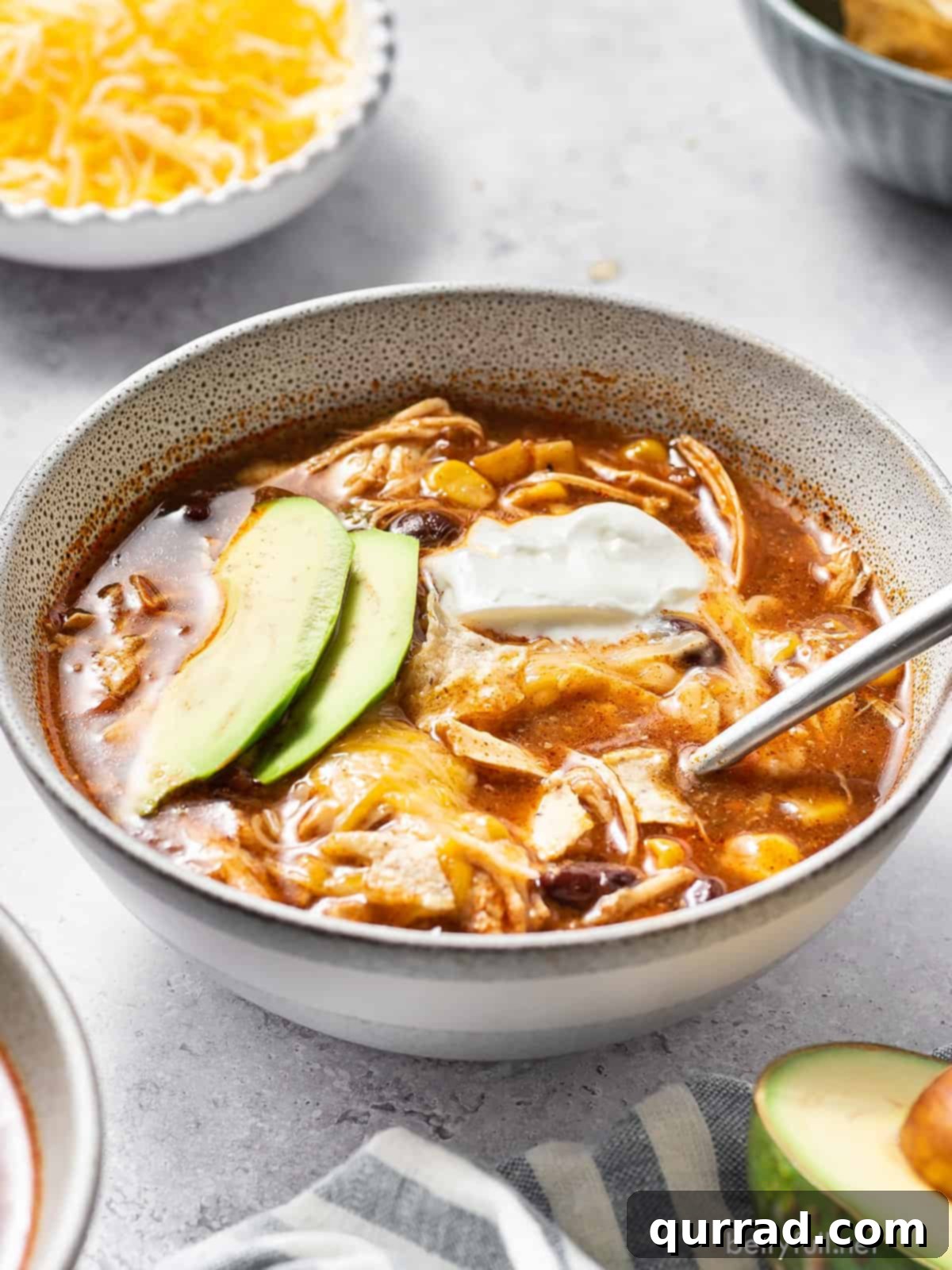 Chicken taco soup in a bowl with avocado slices and sour cream. 