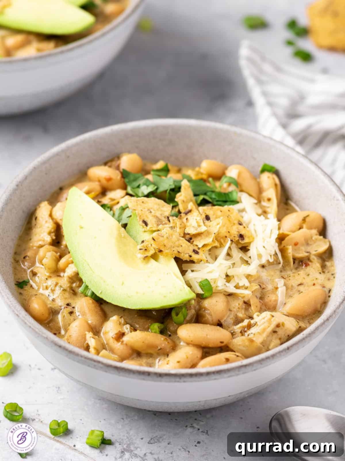 Smoky White Chicken Chili 2 Angled view of white chicken chili, showcasing its creamy texture and vibrant toppings.