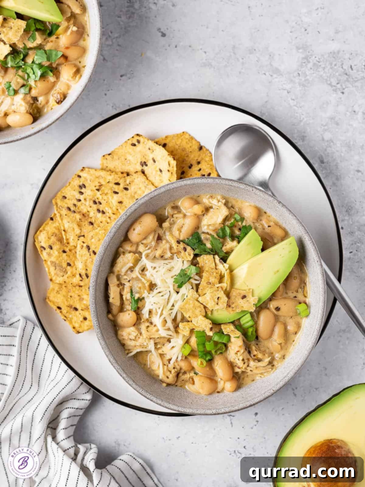 Smoky White Chicken Chili 4 Overhead view of a bowl of white chicken chili, garnished with fresh cilantro and avocado slices.
