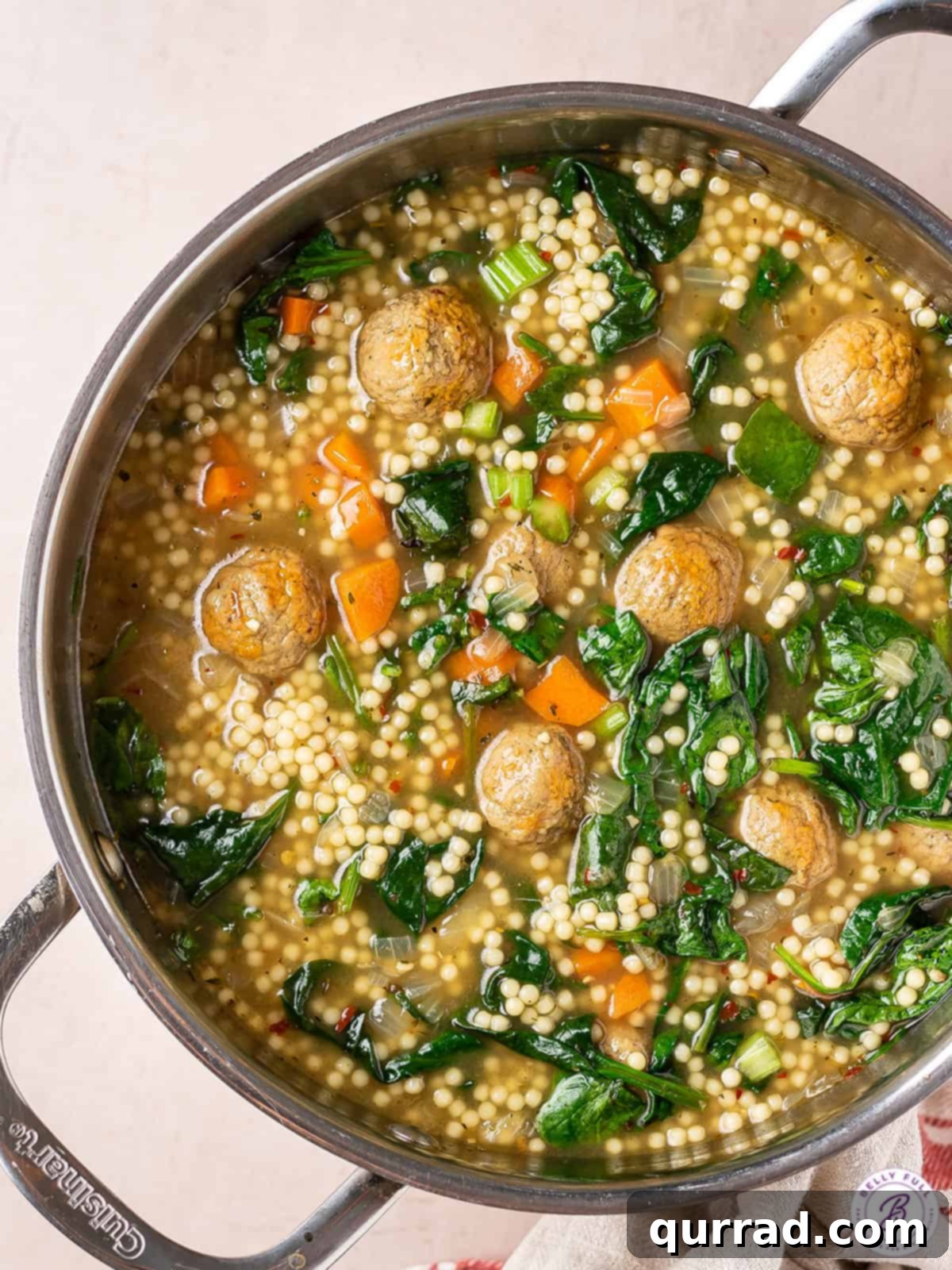Overhead view of a pot of Italian wedding meatball soup, with steam rising.