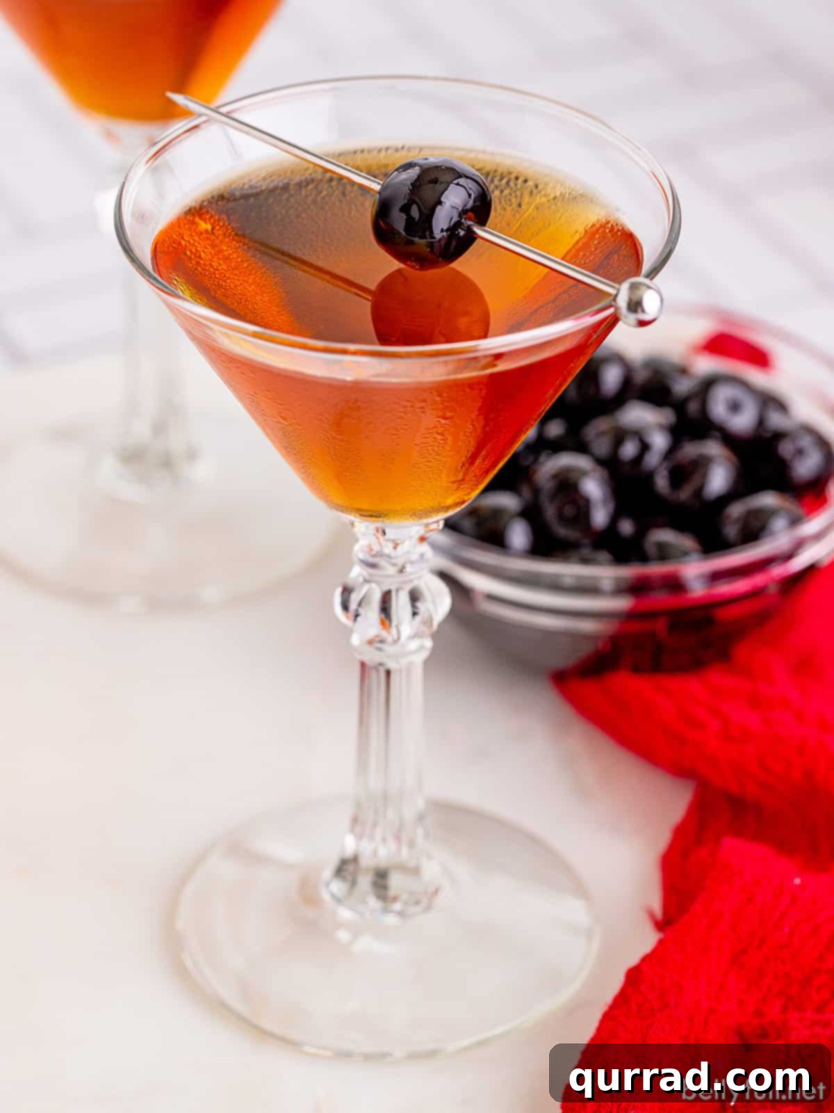A Taste of Old New York 5 An artfully presented Manhattan cocktail in a chilled coupe glass, garnished with a Luxardo cherry, viewed from an overhead angle.