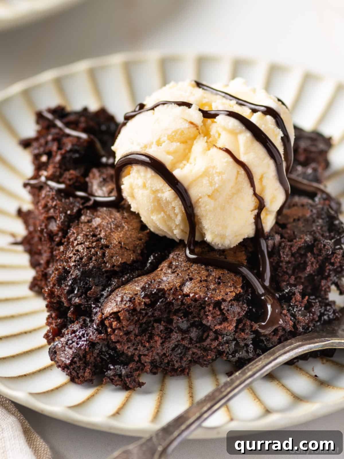 Decadent Chocolate Cobbler 2 A close-up, angled view of a serving of warm chocolate cobbler, elegantly topped with a melting scoop of creamy vanilla ice cream, ready to be enjoyed.