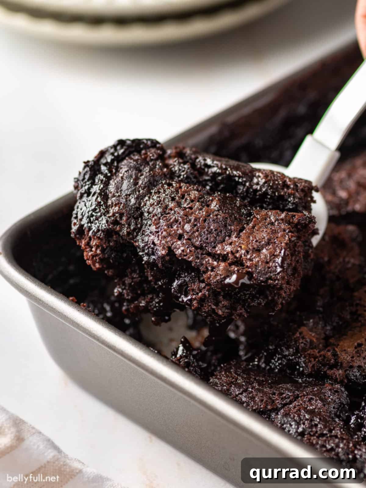 Decadent Chocolate Cobbler 4 A serving spatula carefully lifting a perfect portion of warm, gooey chocolate cobbler from the baking pan, showcasing its rich texture.