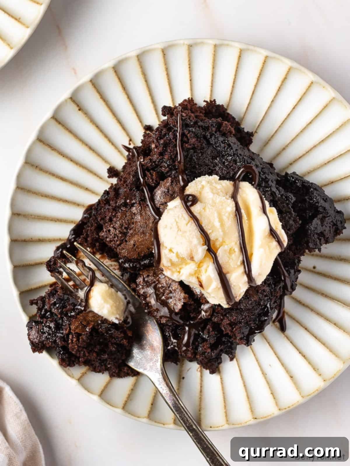 Decadent Chocolate Cobbler 5 An overhead shot of a single serving of chocolate cobbler, perfectly plated on a white dish and crowned with a scoop of melting vanilla ice cream.