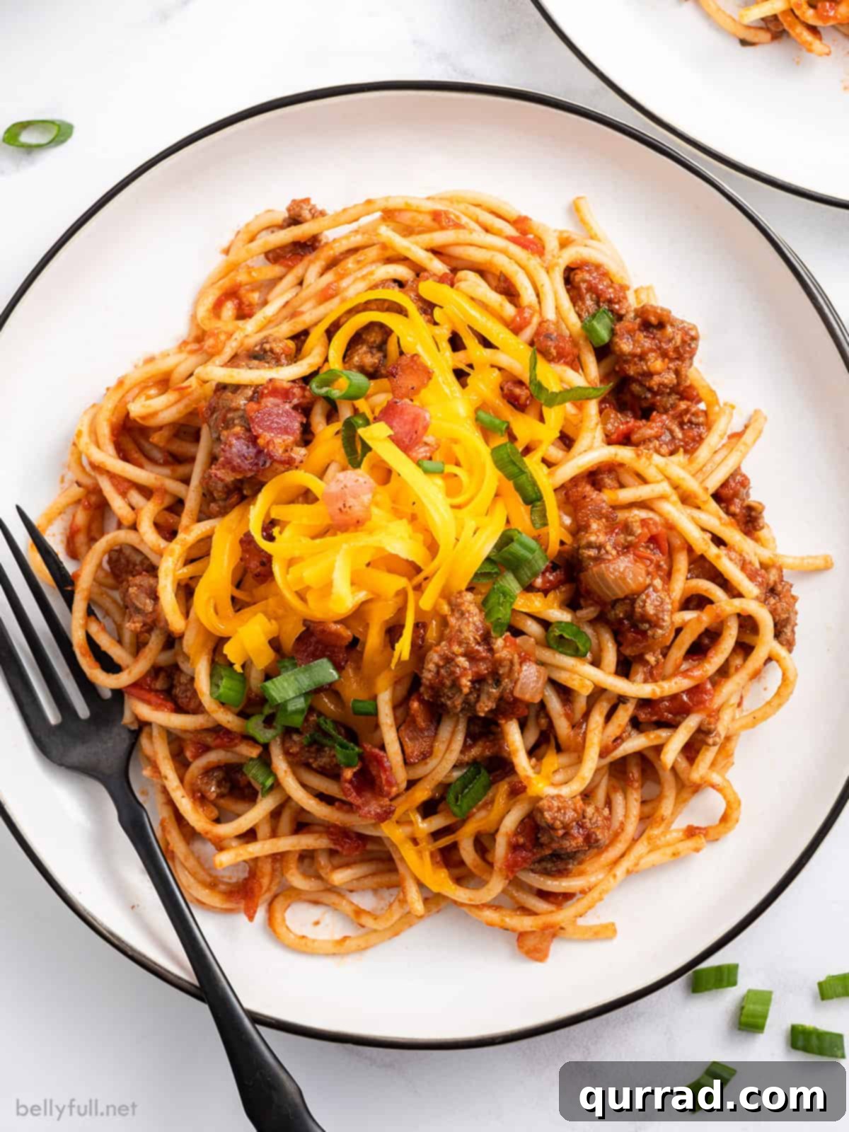 Chuckwagon Pasta 2 Overhead view of a plate of cowboy spaghetti with crispy bacon and melted cheddar cheese