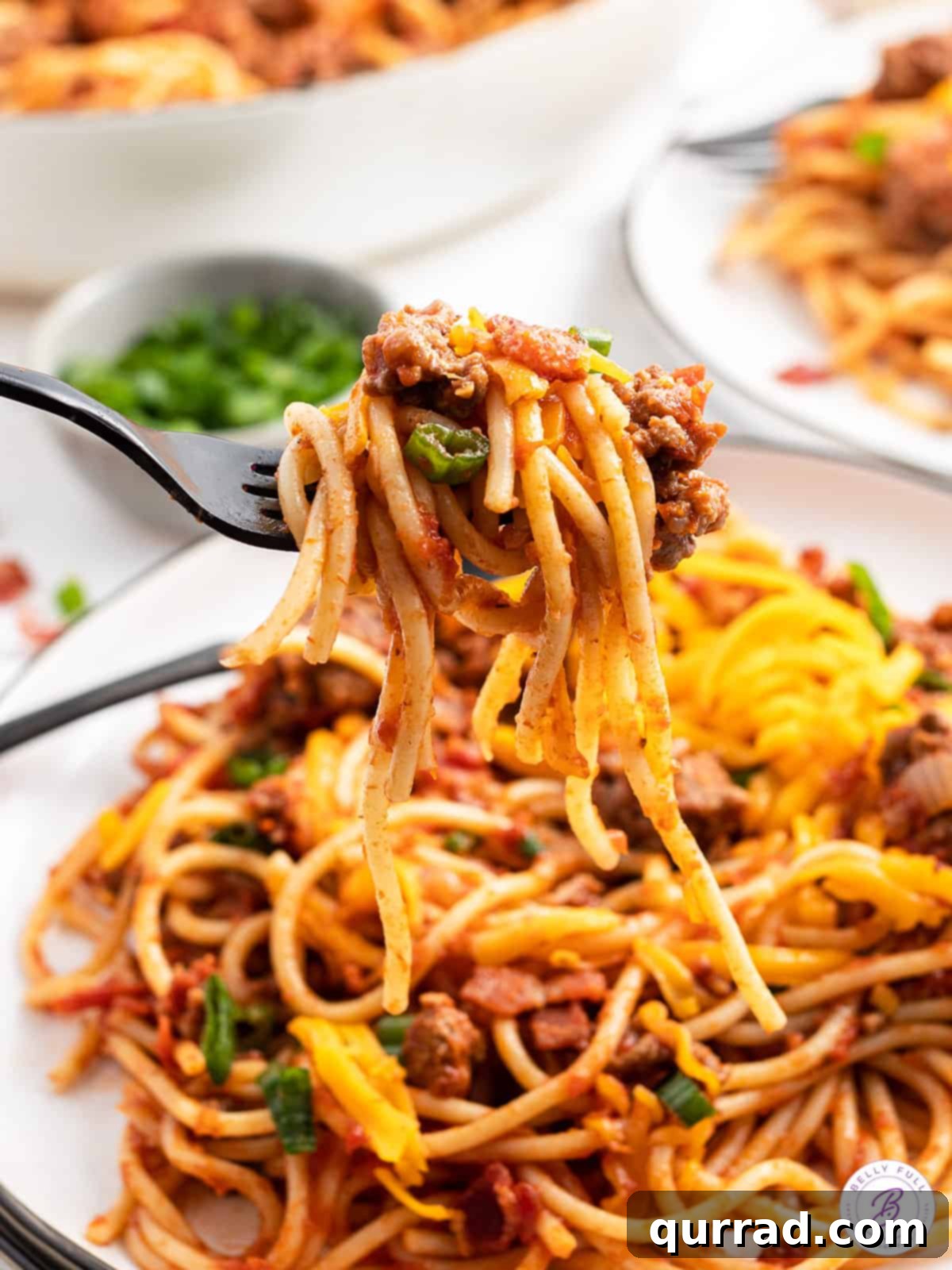 Chuckwagon Pasta 4 A fork full of cowboy spaghetti over a plate of it, showing melted cheese and meat sauce