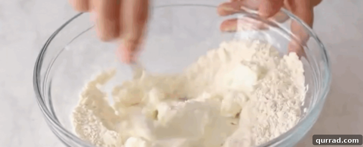 Preparing the bagel dough by mixing flour, baking powder, salt, and Greek yogurt in a bowl.
