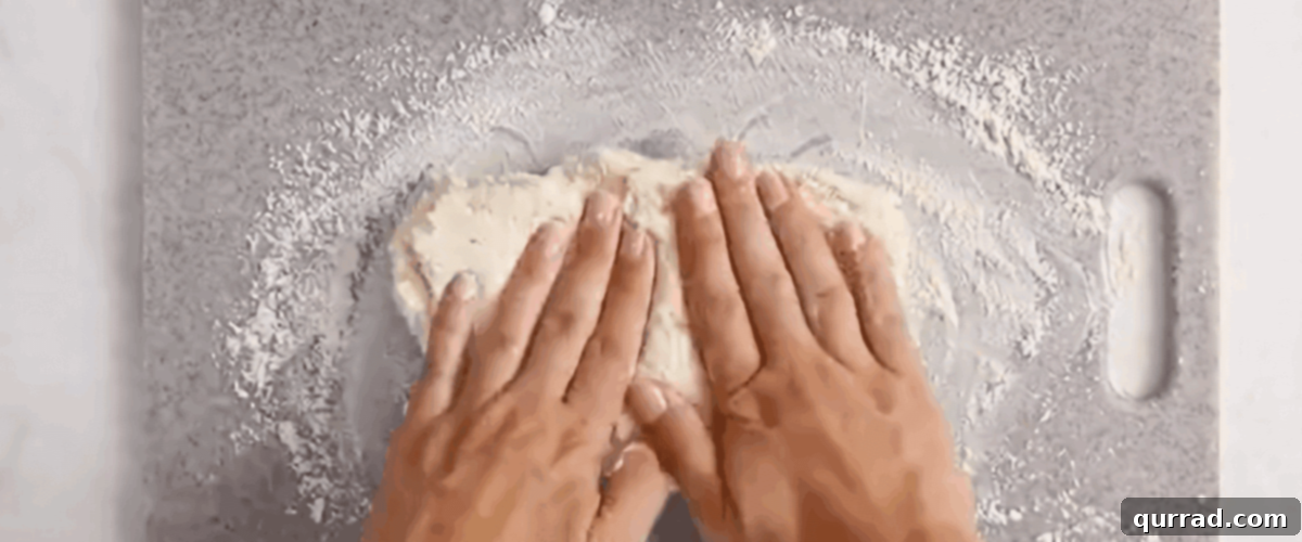 Kneading the bagel dough on a floured surface until smooth and cohesive.