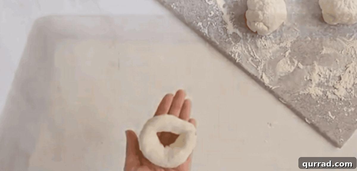 Hands shaping a bagel by rolling dough into a rope and sealing the ends to form a circle.
