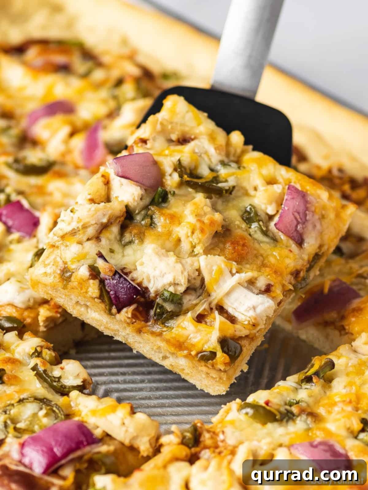 Signature BBQ Chicken Pizza 2 A perfectly baked slice of BBQ chicken pizza, showcasing its golden crust, melted cheese, and generous chicken and topping distribution, being served fresh from the pan.