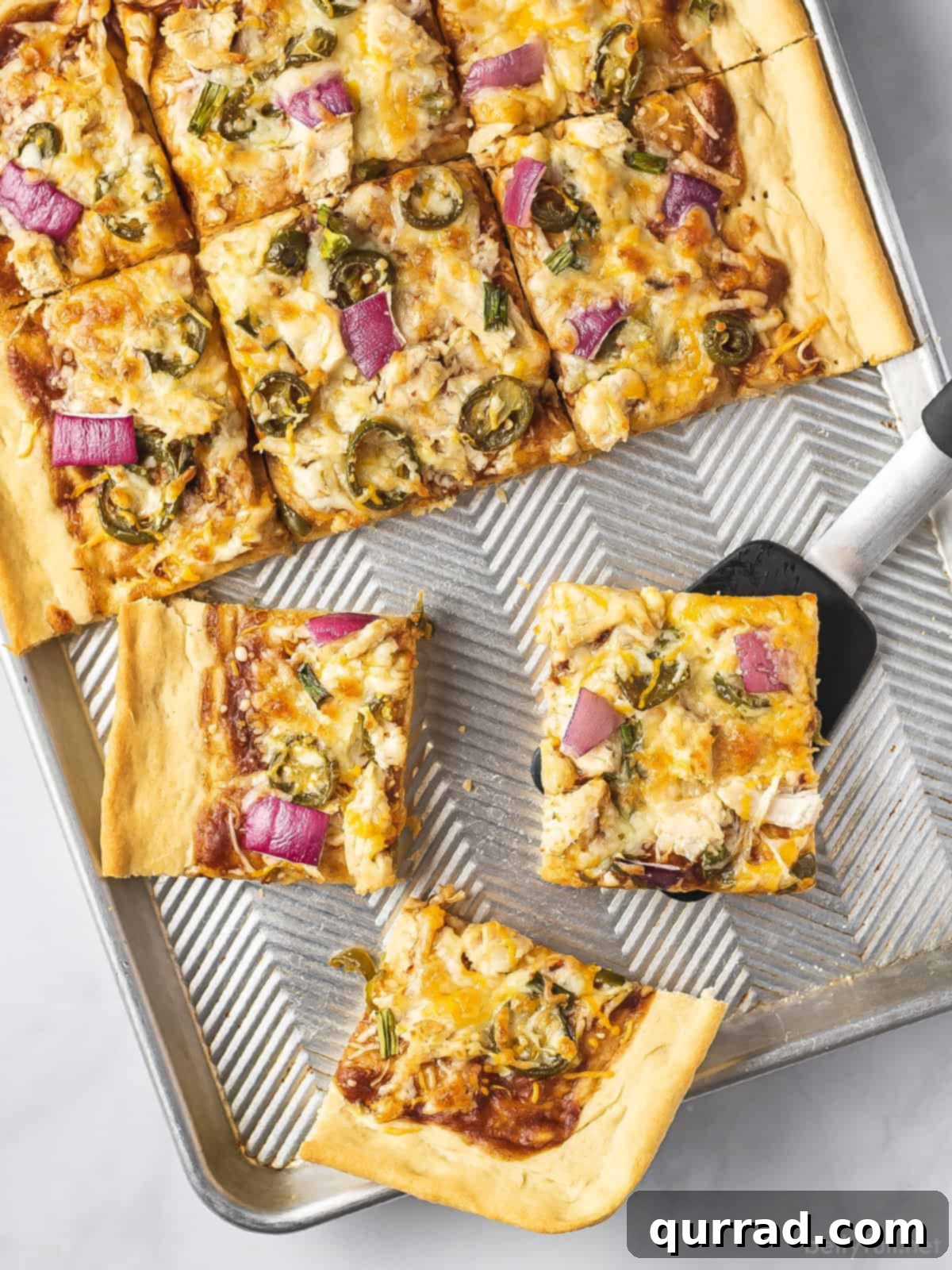 Signature BBQ Chicken Pizza 3 An overhead view of a freshly baked BBQ chicken sheet pan pizza with several slices removed, highlighting the crispy crust and abundant toppings.