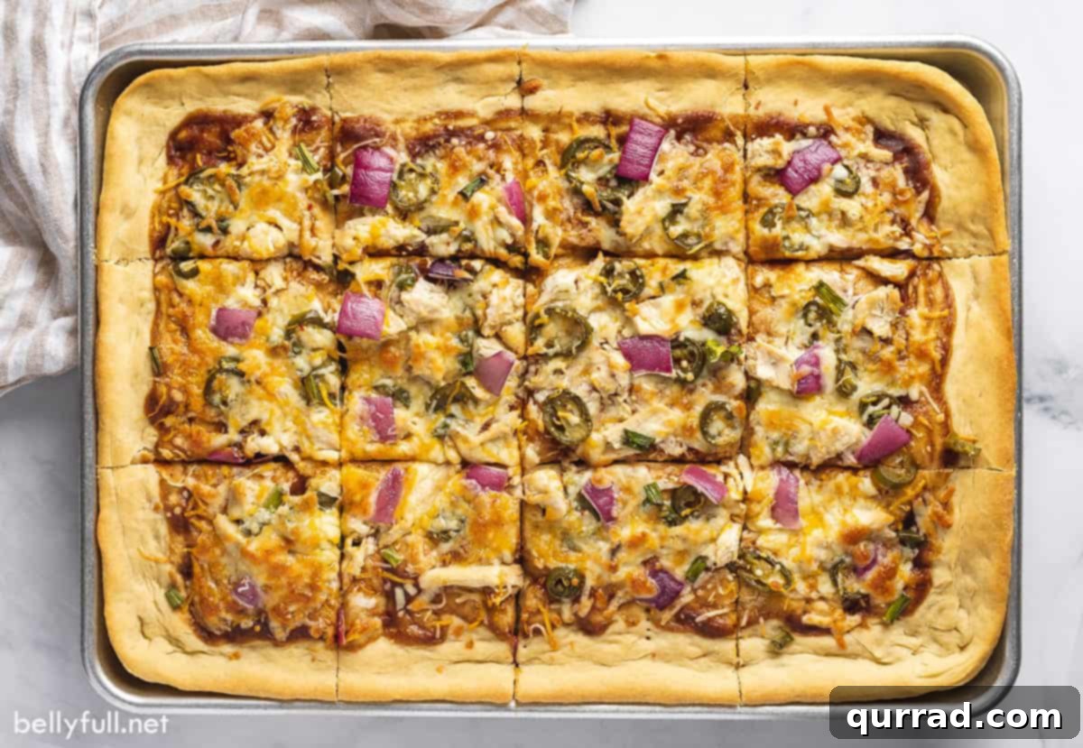Signature BBQ Chicken Pizza 4 A top-down view of a vibrant BBQ chicken pizza on a sheet pan before being sliced, showcasing the evenly distributed toppings and golden-brown crust.