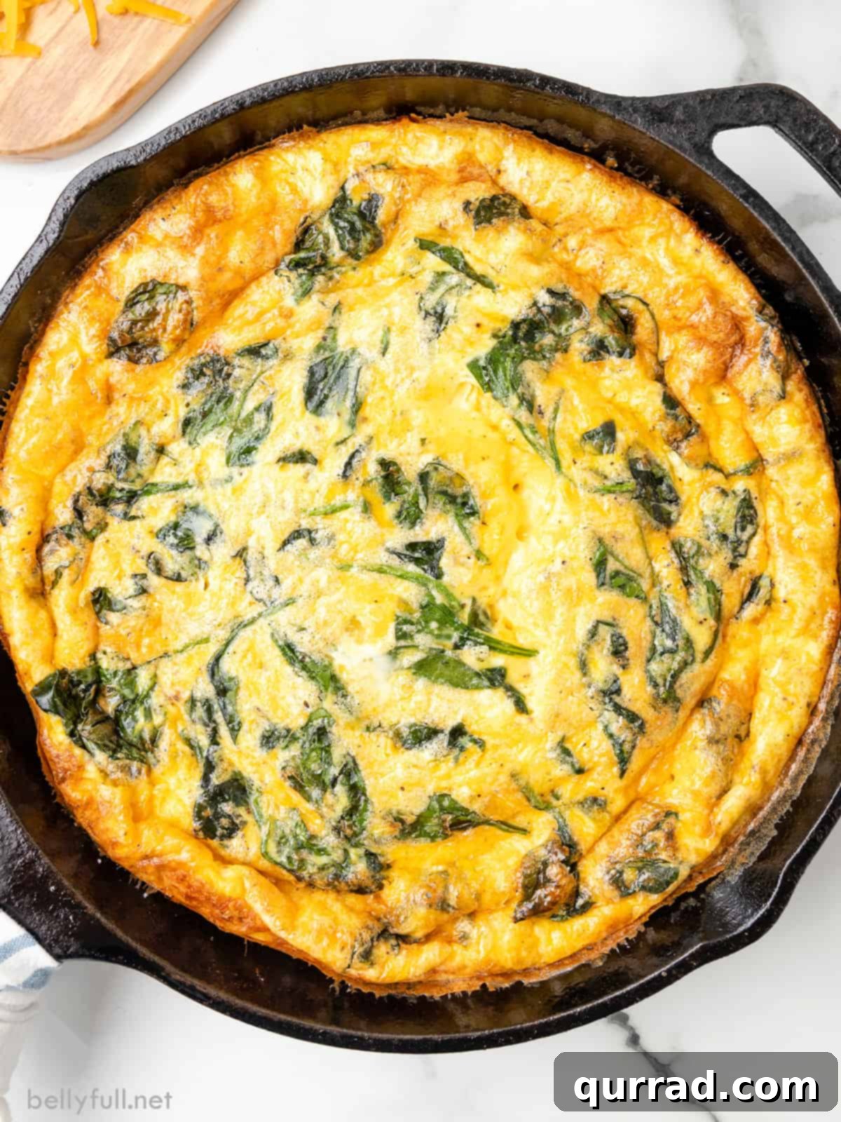 Hearty Ham and Spinach Frittata Skillet 2 Overhead view of a spinach frittata in a cast iron skillet, golden brown and garnished.