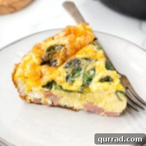 A slice of ham and cheese frittata on a white plate