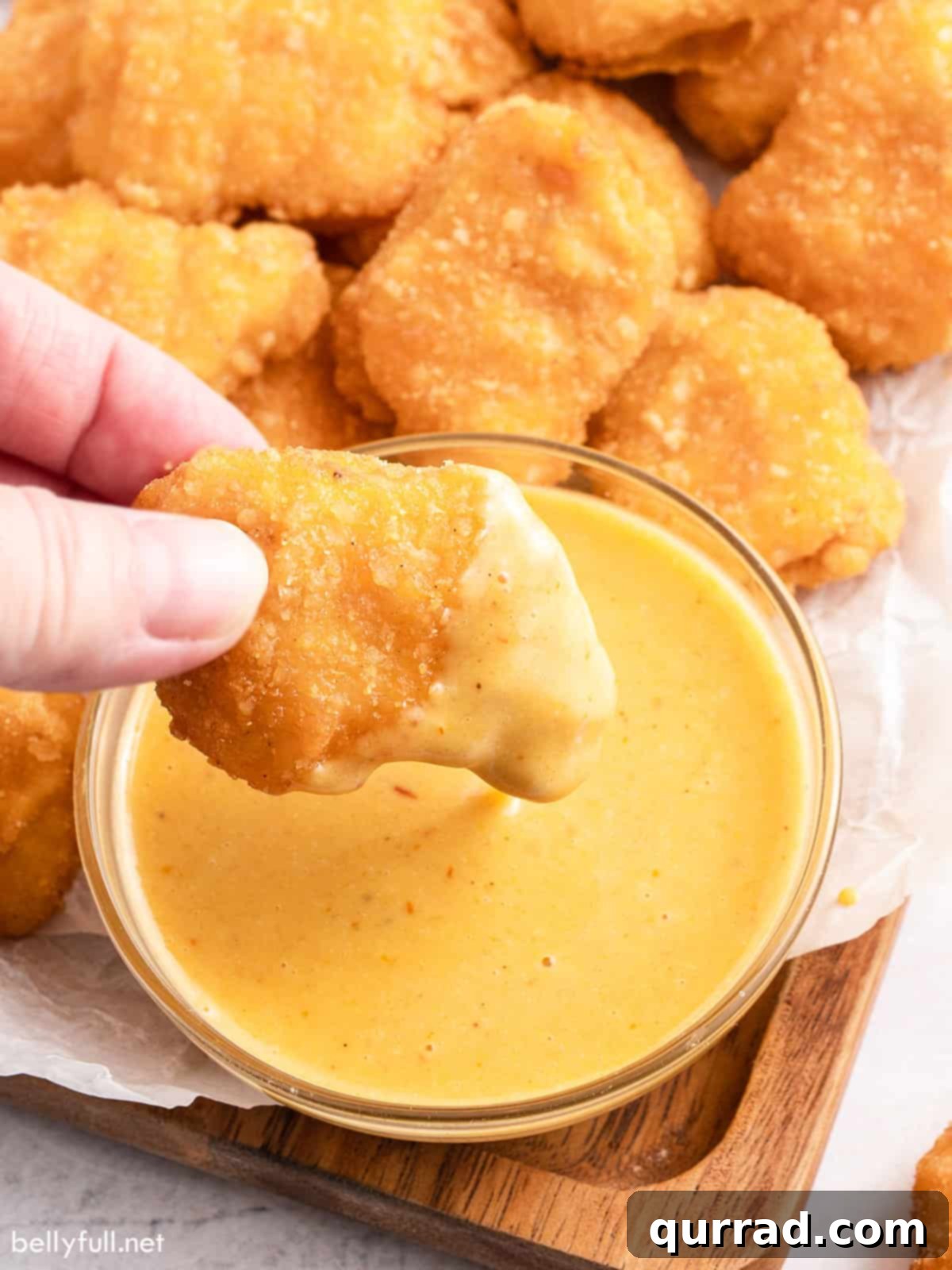 Homemade Chick-fil-A Style Sauce 4 A hand dipping a crispy chicken nugget into a bowl of homemade Chick-fil-A sauce