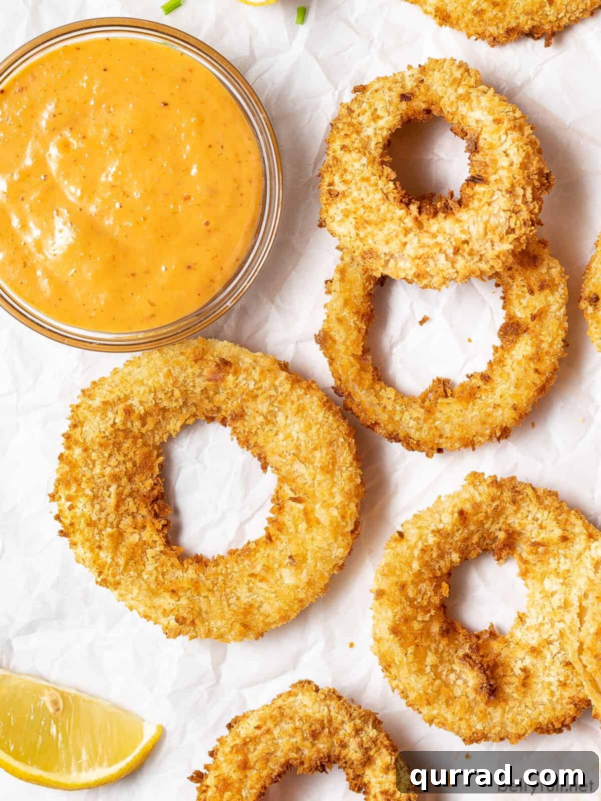 Overhead view of air fryer onion rings next to a dish of remoulade