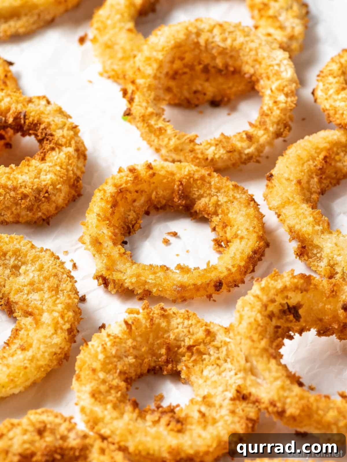 Angled view of air fryer onion rings on a white background
