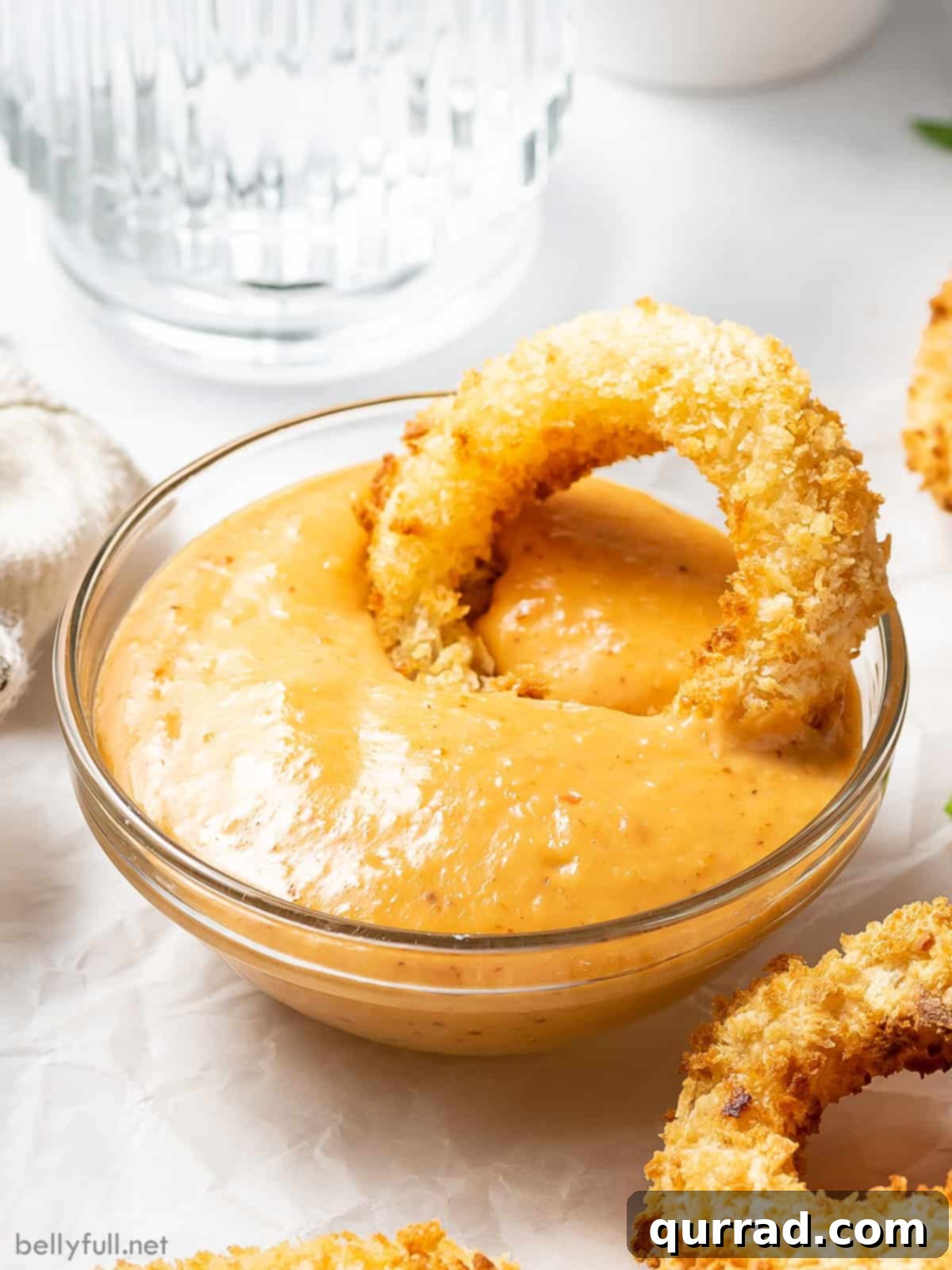 An air fryer onion ring in a dish of remoulade