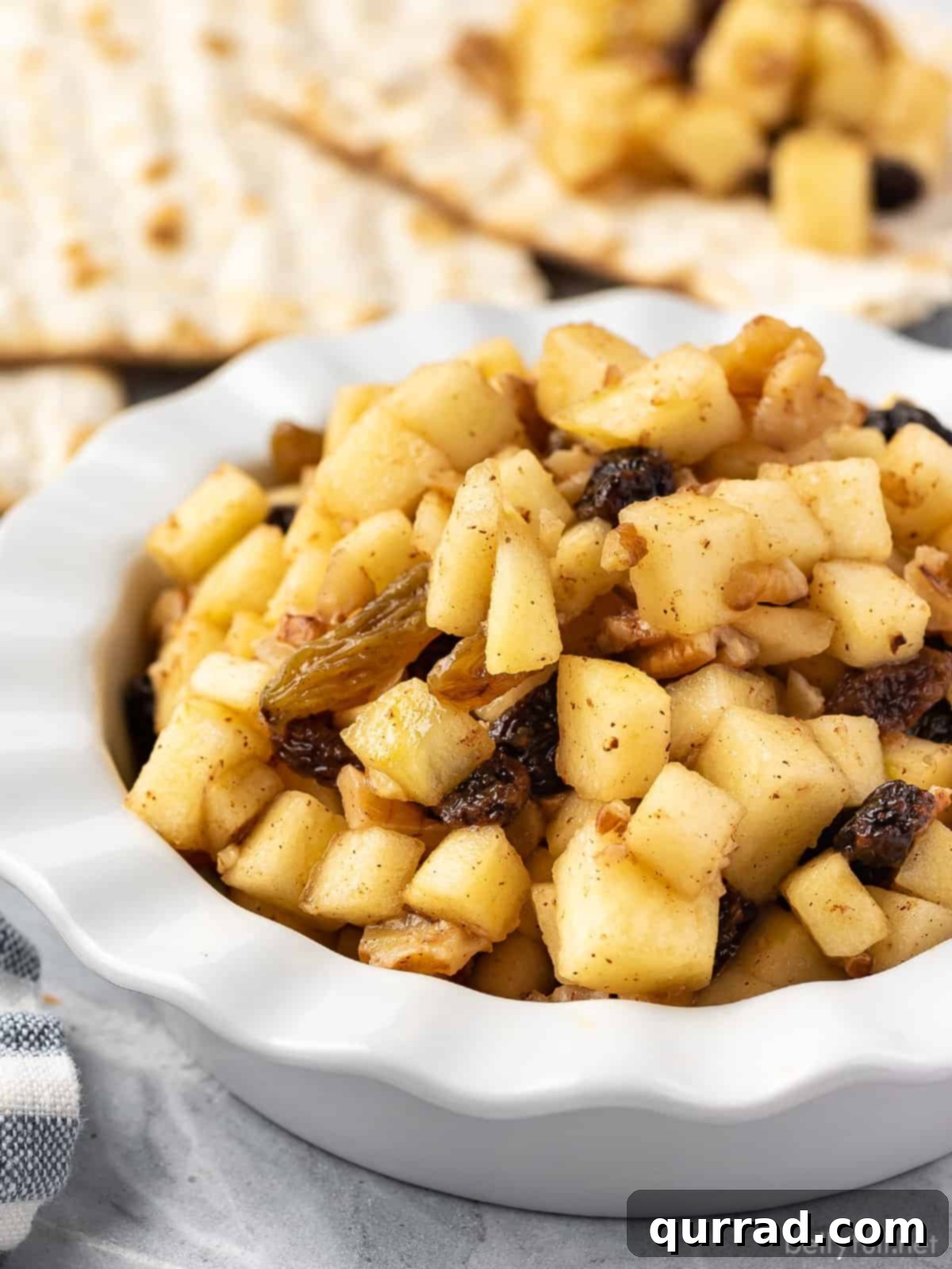 Sweet Paste of Passover 4 A pristine white bowl showcasing a vibrant mix of finely chopped apples, plump raisins, and crunchy nuts, ready to be seasoned for Charoset.