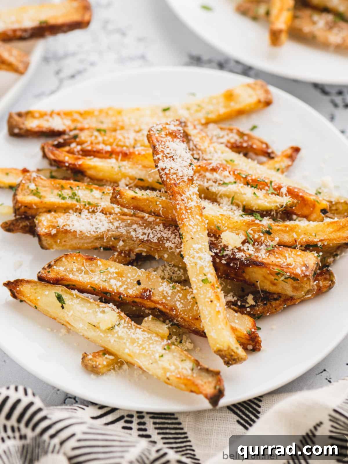Crispy Air-Fried Garlic Parmesan Fries 3 Angled view of a plate overflowing with golden, crispy air fryer french fries, ready to be enjoyed.