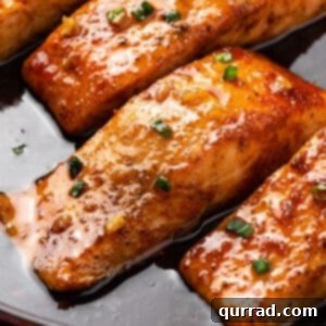 Close-up of golden honey glazed salmon in a skillet with sauce.