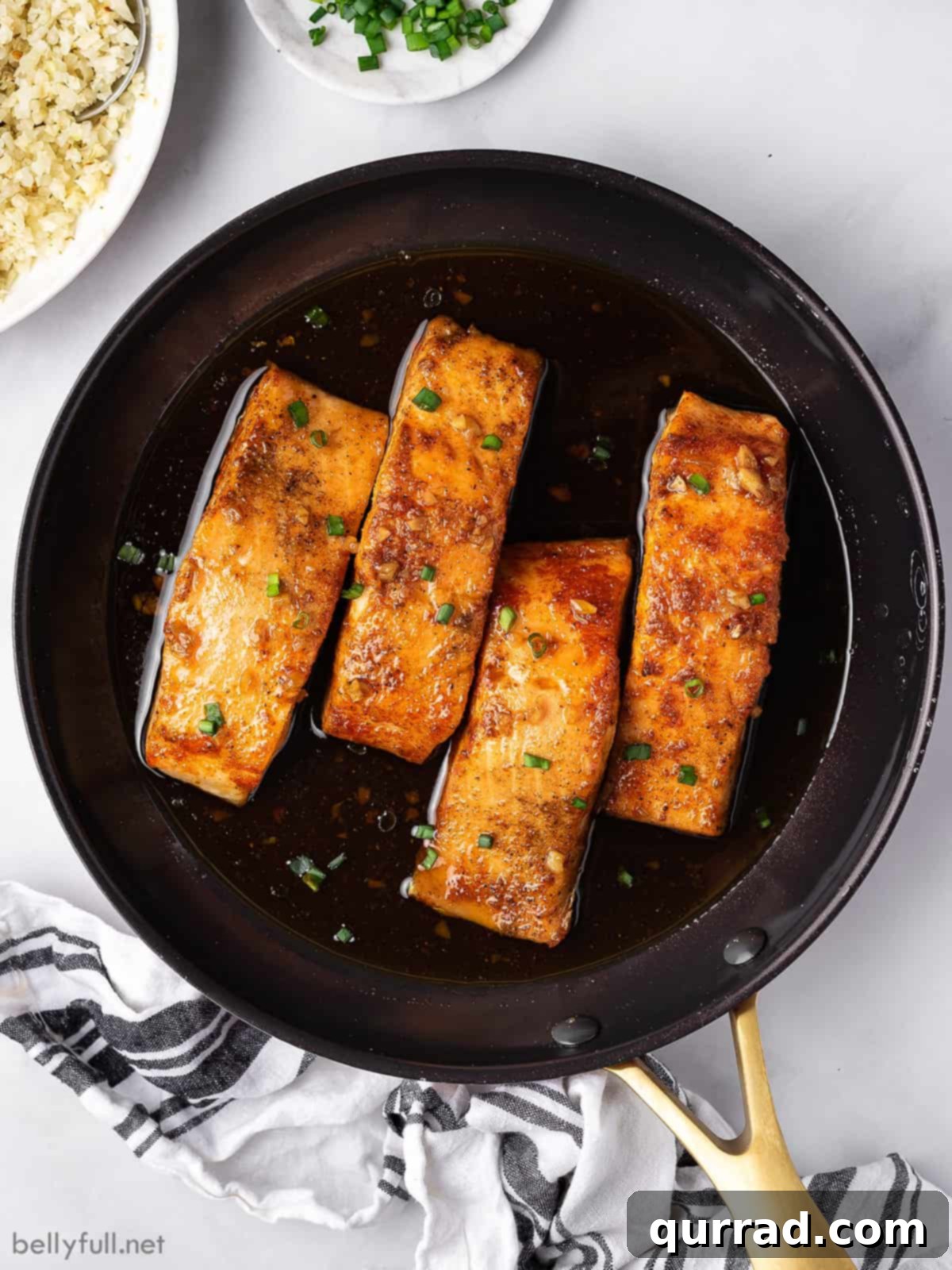 Overhead view of four perfectly cooked honey glazed salmon fillets in a skillet, ready to serve.