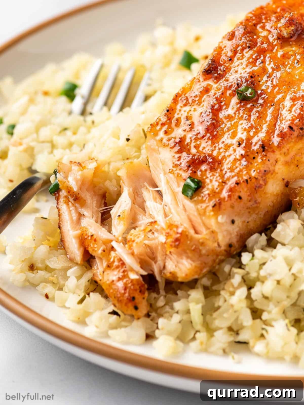 A fork flaking a piece of moist, honey glazed salmon, showing its perfect doneness.