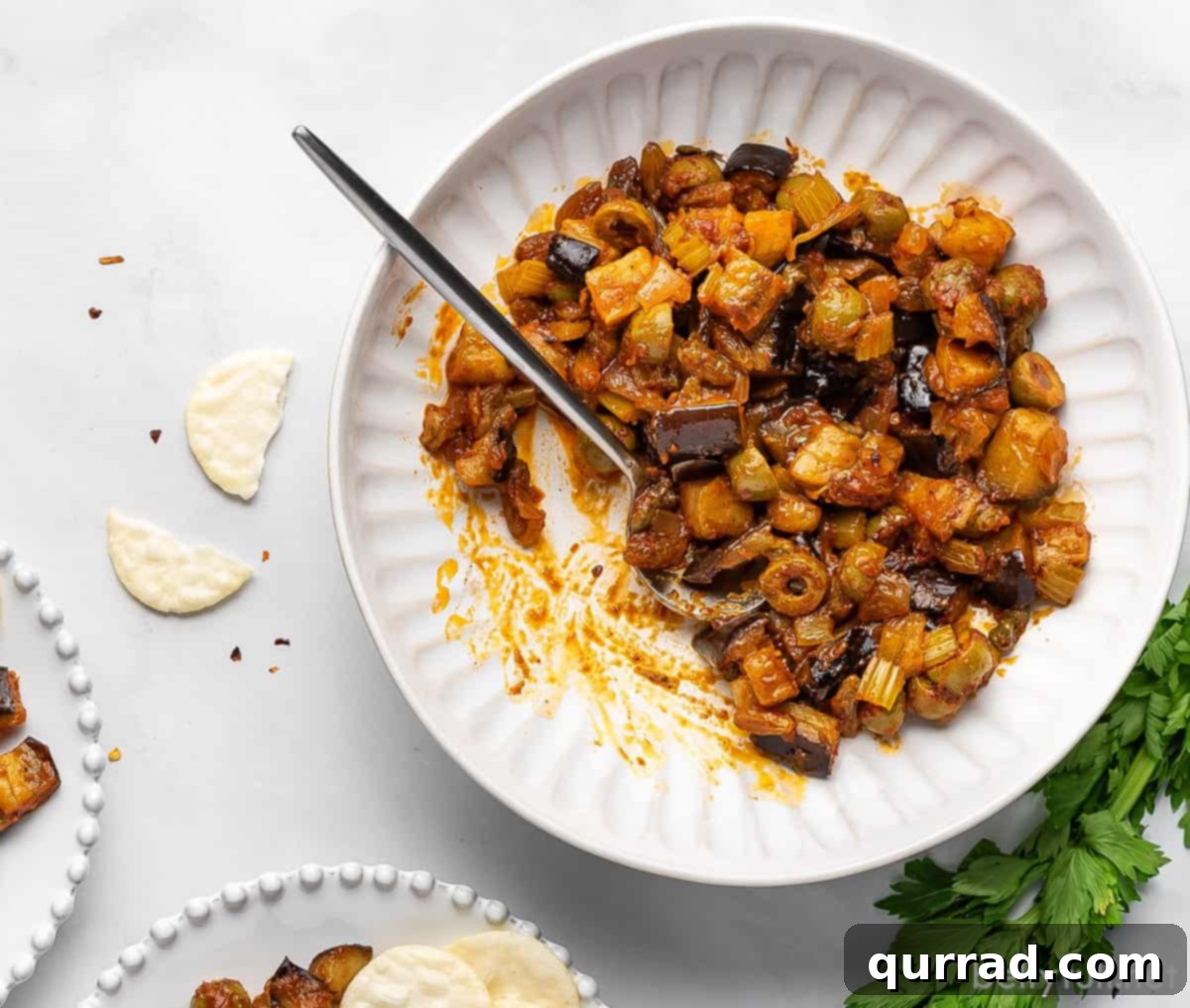 overhead eggplant caponata in white bowl with spoon