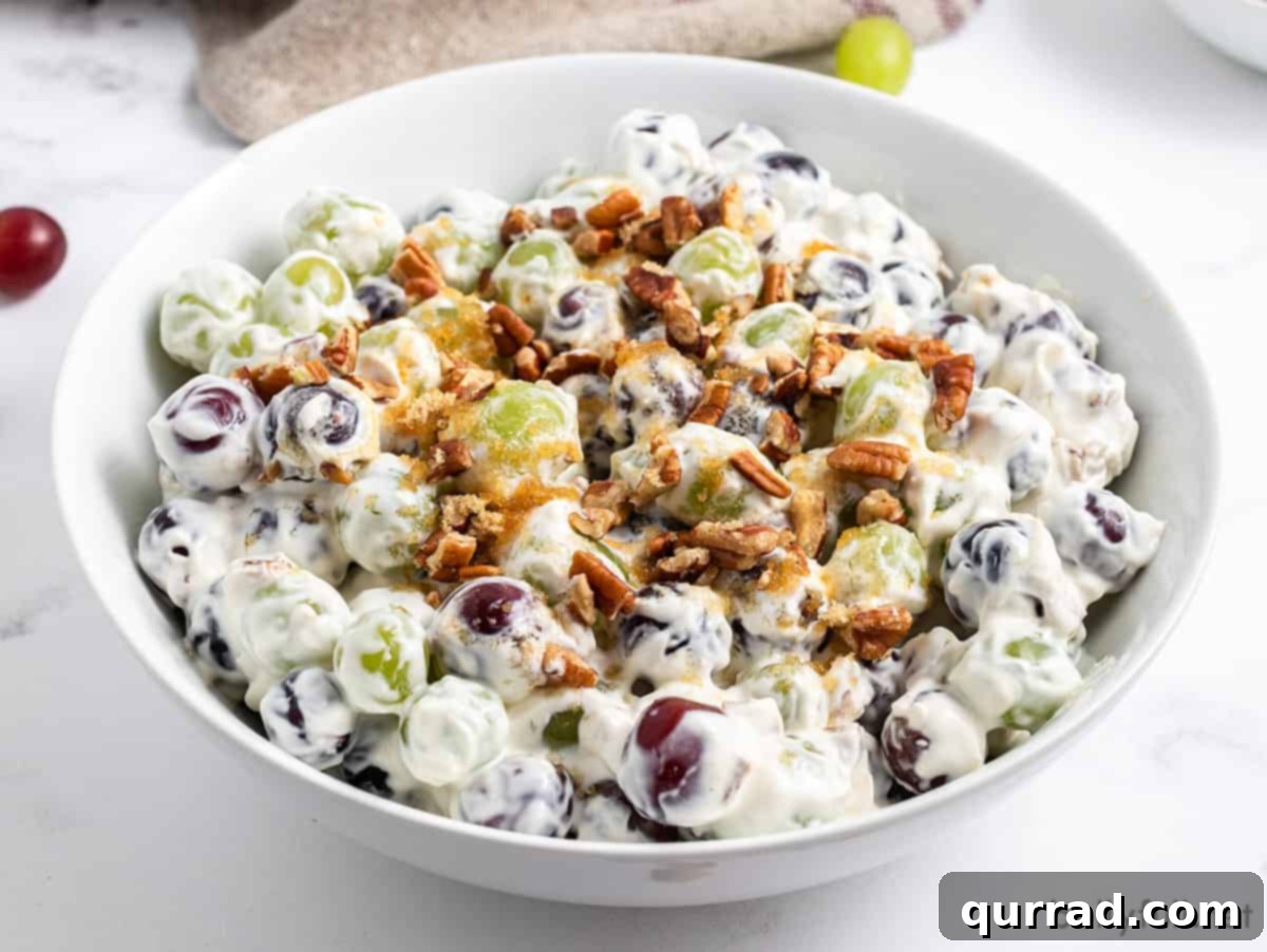 Angled overhead view of a bowl of grape salad with a serving spoon.
