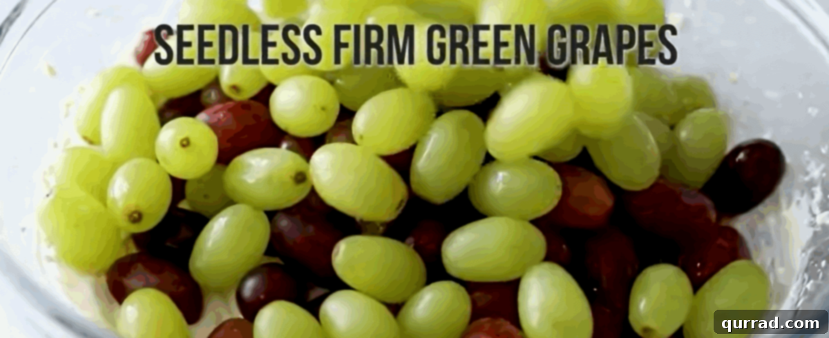 Adding washed red and green grapes to the bowl of creamy dressing.