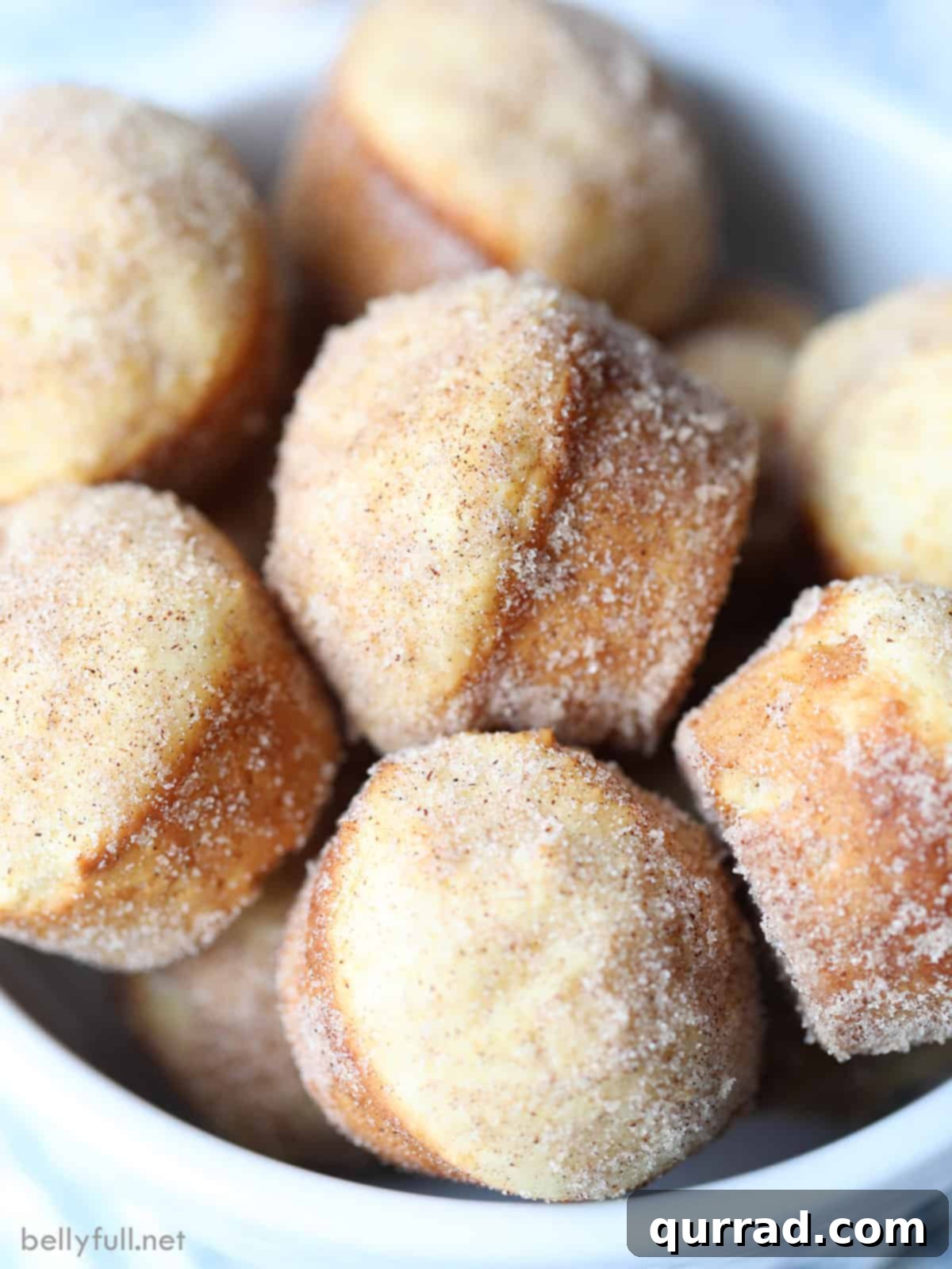Cinnamon Sugar Donut Muffins 3 A bowl filled with freshly baked, cinnamon sugar coated mini donut muffins, inviting a delightful snack.