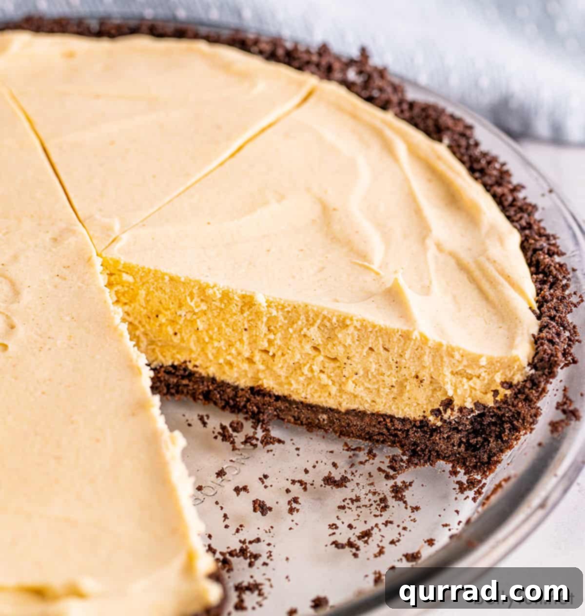 Chilled Peanut Butter Perfection 3 A whole No Bake Peanut Butter Pie resting in a glass pie dish, with a single slice perfectly removed, revealing the dark chocolate crust and the thick, pale peanut butter filling. The edges of the pie are neatly defined.