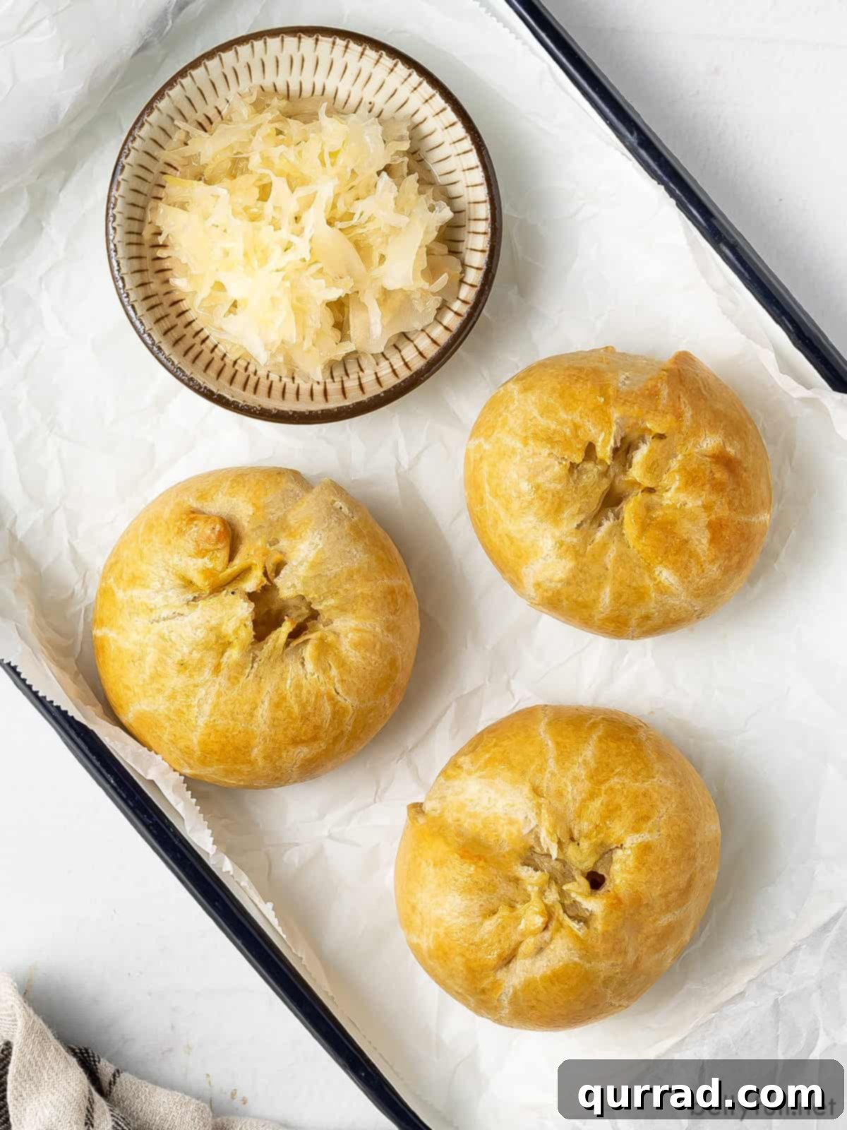 Flaky Potato Pastry 8 overhead 3 knish on serving tray with bowl of sauerkraut