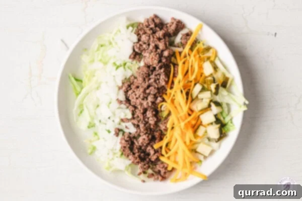 A composed Big Mac Salad bowl showing distinct rows of iceberg lettuce, ground beef, cheese, onions, and pickles before dressing.