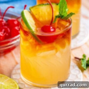 Overhead angled view of a Mai Tai cocktail garnished with lime, pineapple, and a cherry