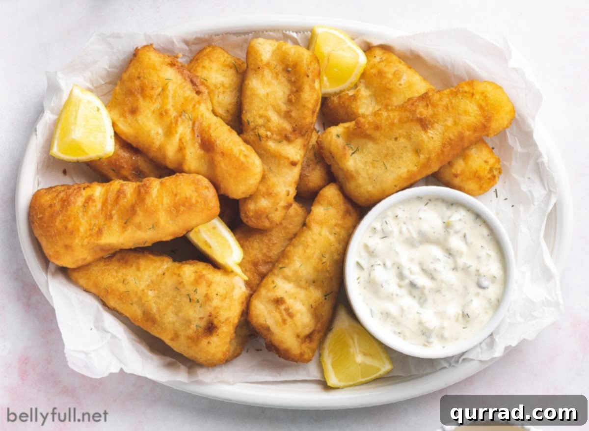 Zesty Fish Dip 5 Overhead view of a white plate featuring crispy fish sticks generously dipped into a bowl of homemade tartar sauce
