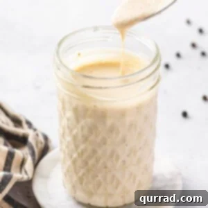 A glass jar with a spoon of Alabama white sauce above it
