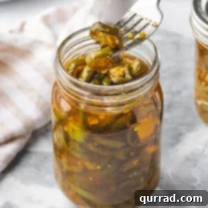 A fork with a candied jalapeno over a jar of cowboy candy