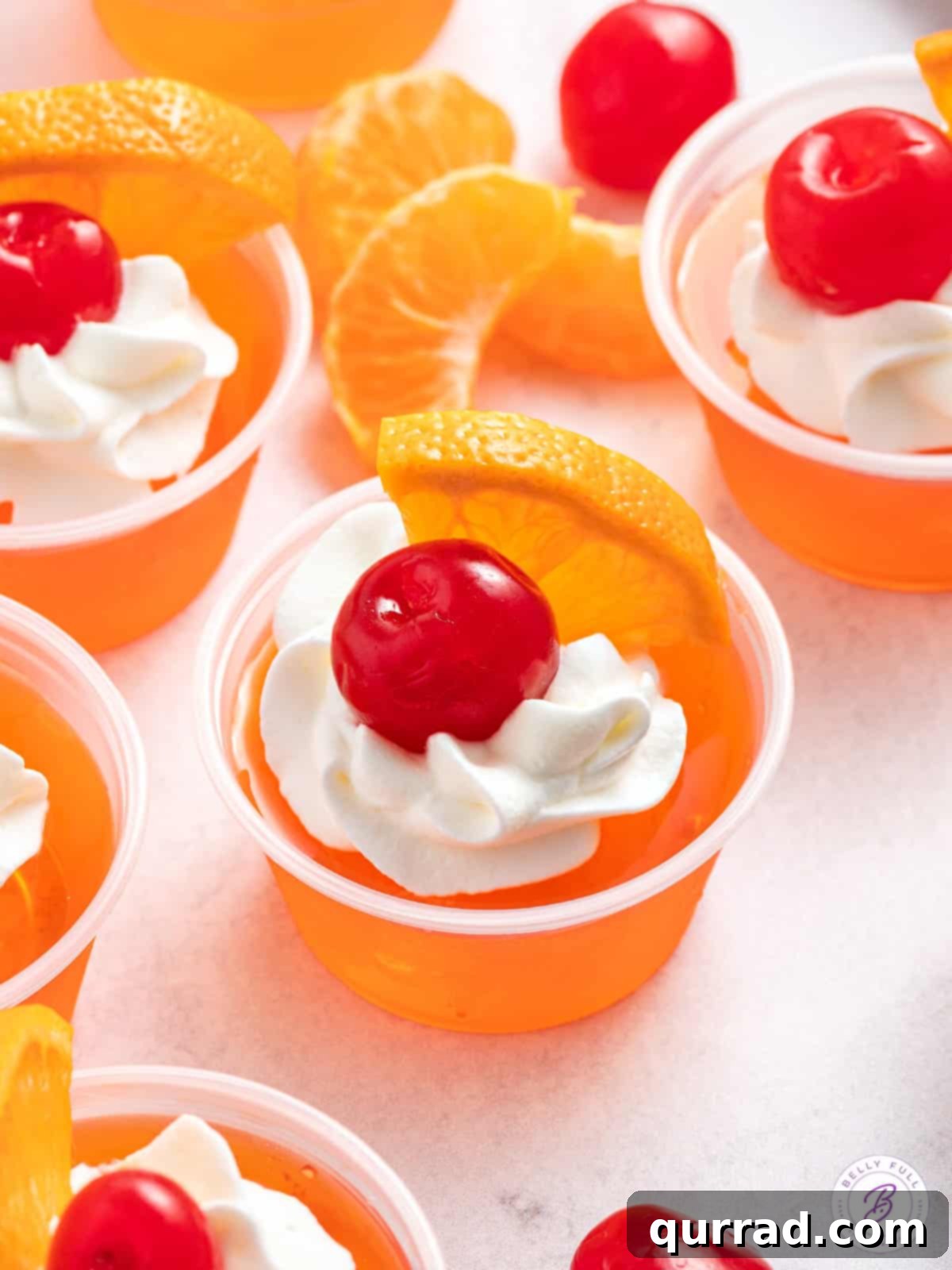 Tropical Sunset Gelatin Shots 2 Sex on the Beach jello shots elegantly garnished with a swirl of whipped cream, a fresh orange wedge, and a ruby-red maraschino cherry.
