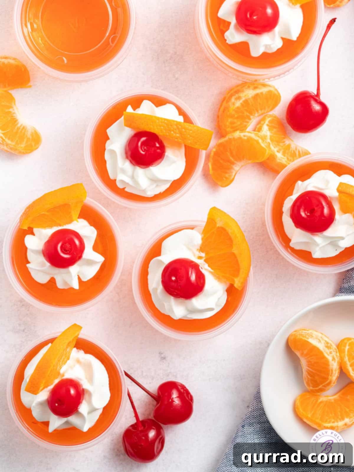 Tropical Sunset Gelatin Shots 4 Close-up of several orange jello shots, each beautifully garnished with whipped cream, an orange slice, and a maraschino cherry, ready to be enjoyed.