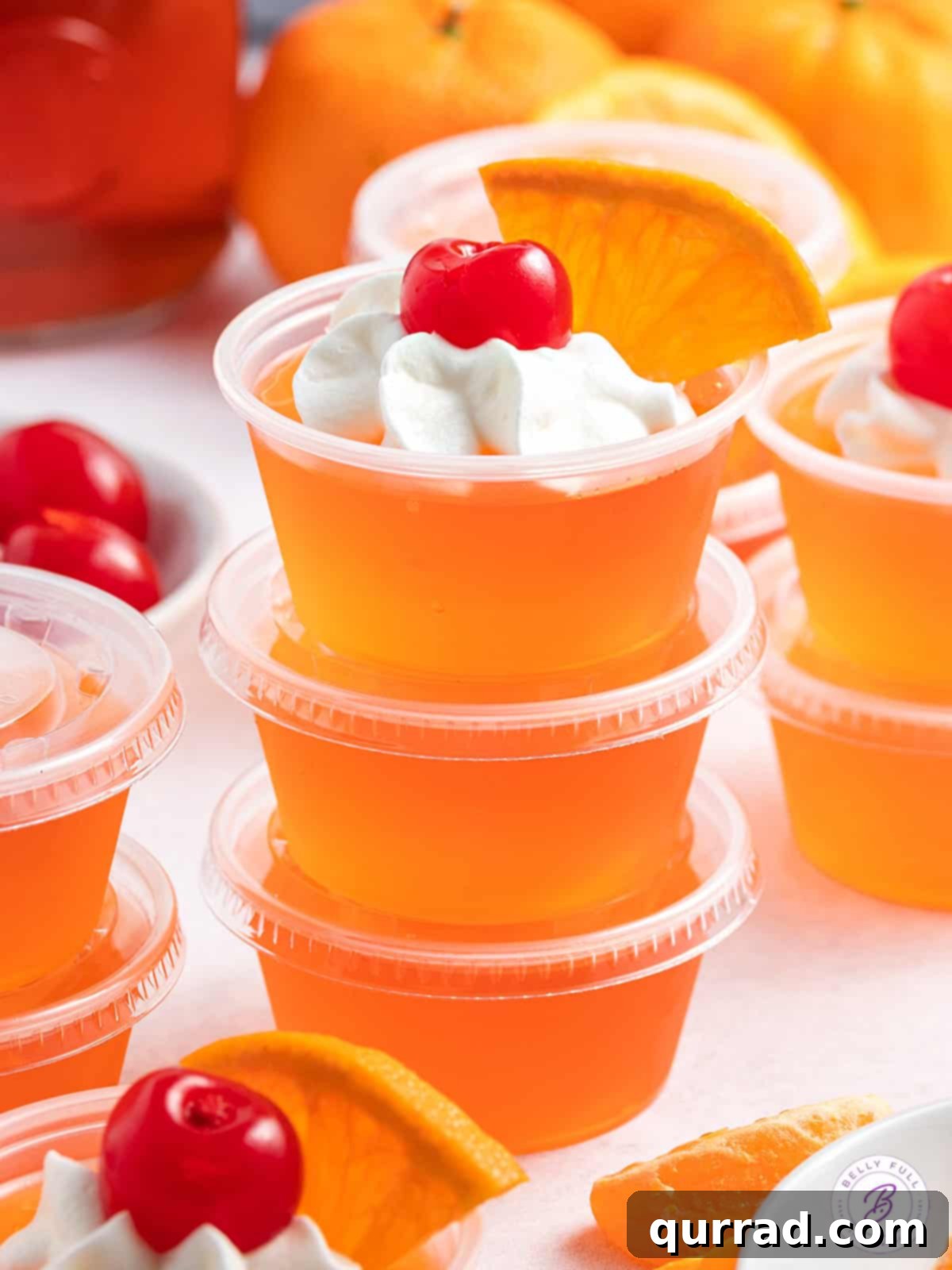 Tropical Sunset Gelatin Shots 5 A stack of three bright orange Sex on the Beach jello shots in clear plastic cups, showcasing their vibrant color and neat layers.