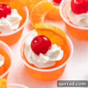 sex on the beach jello shots garnished with whipped cream, orange wedge, and maraschino cherry