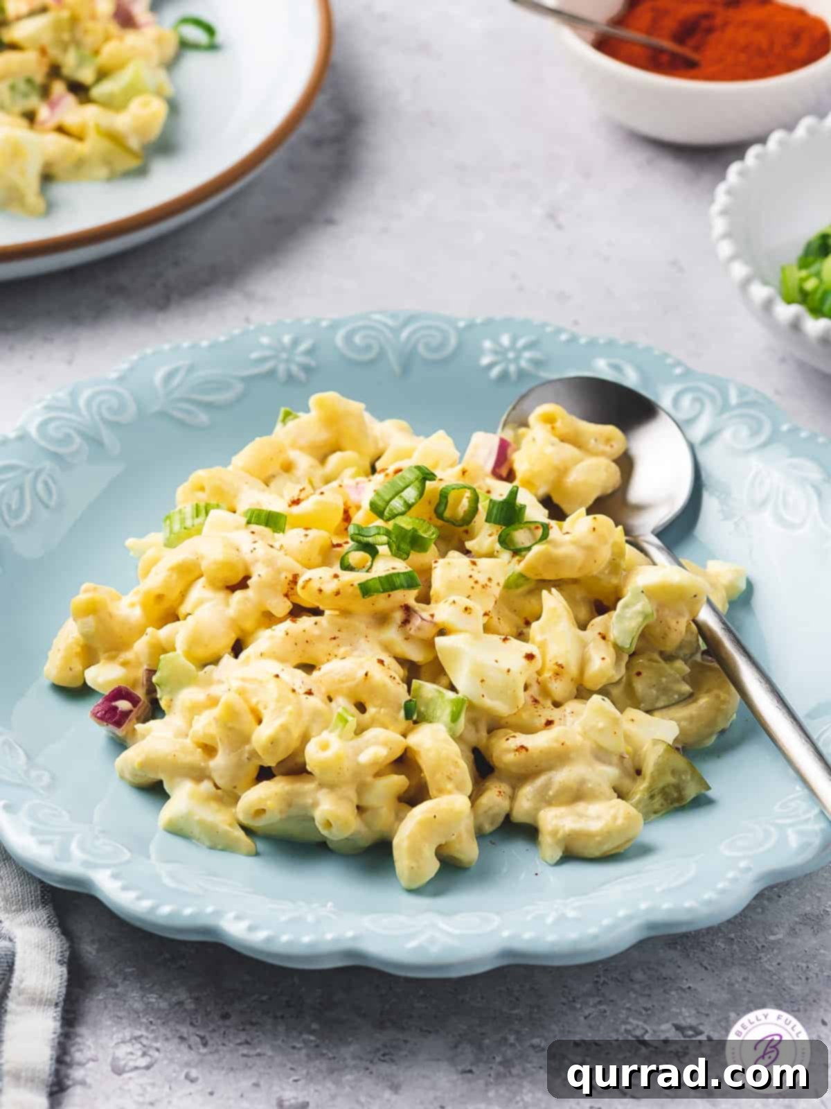 Angled view of a blue plate with a generous portion of deviled egg pasta salad, showing its creamy texture and visible pieces of egg and vegetables