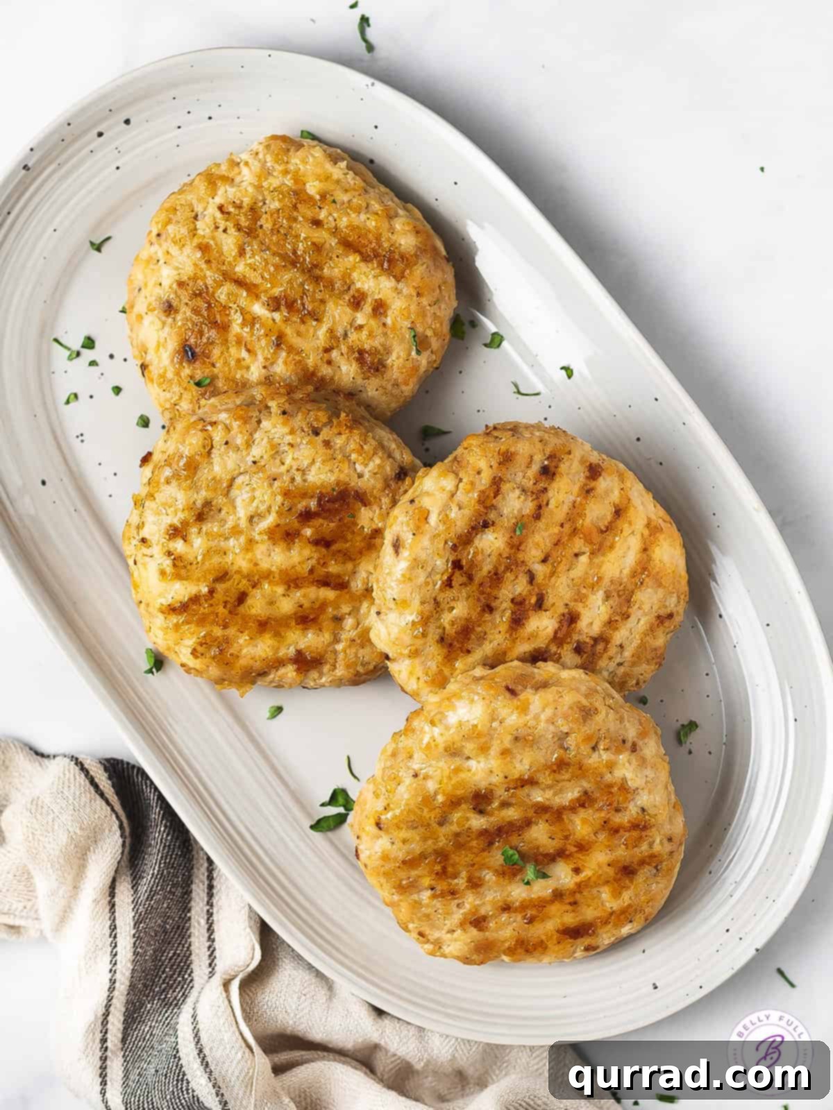 Beyond Basic Chicken Burgers 4 Overhead view of ground chicken burgers on a white serving platter, garnished and ready