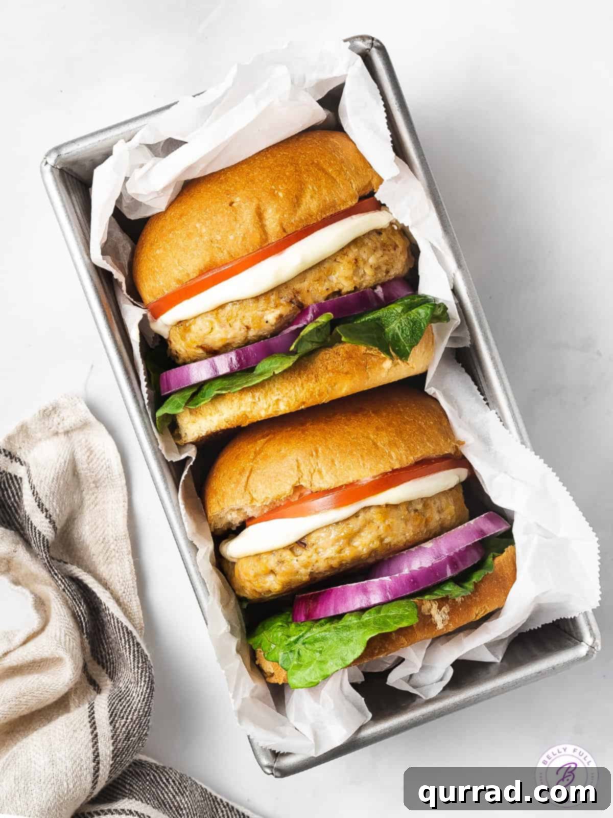 Beyond Basic Chicken Burgers 5 Overhead view of two homemade chicken burgers on their sides on buns, garnished with fresh ingredients