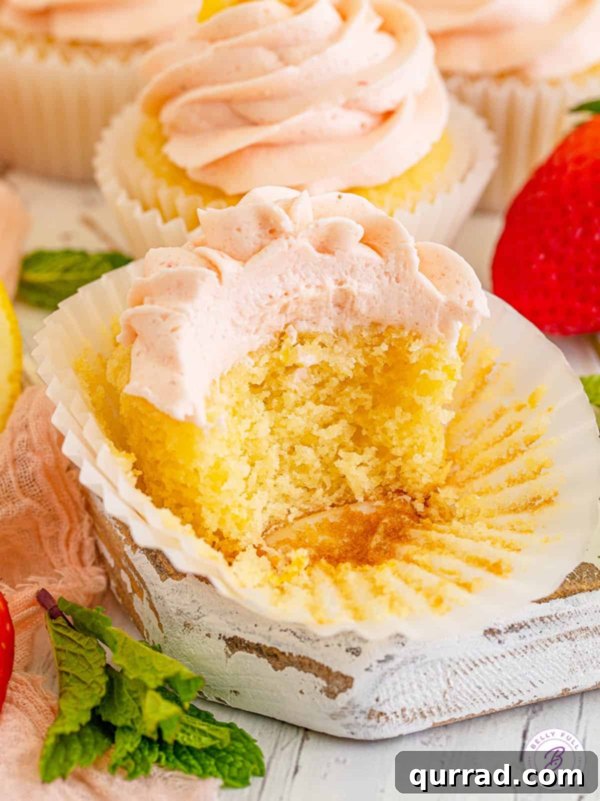 Bright Lemon Zing Cupcakes 5 A half-eaten lemon cupcake with a generous swirl of pink strawberry buttercream, showing the moist interior.