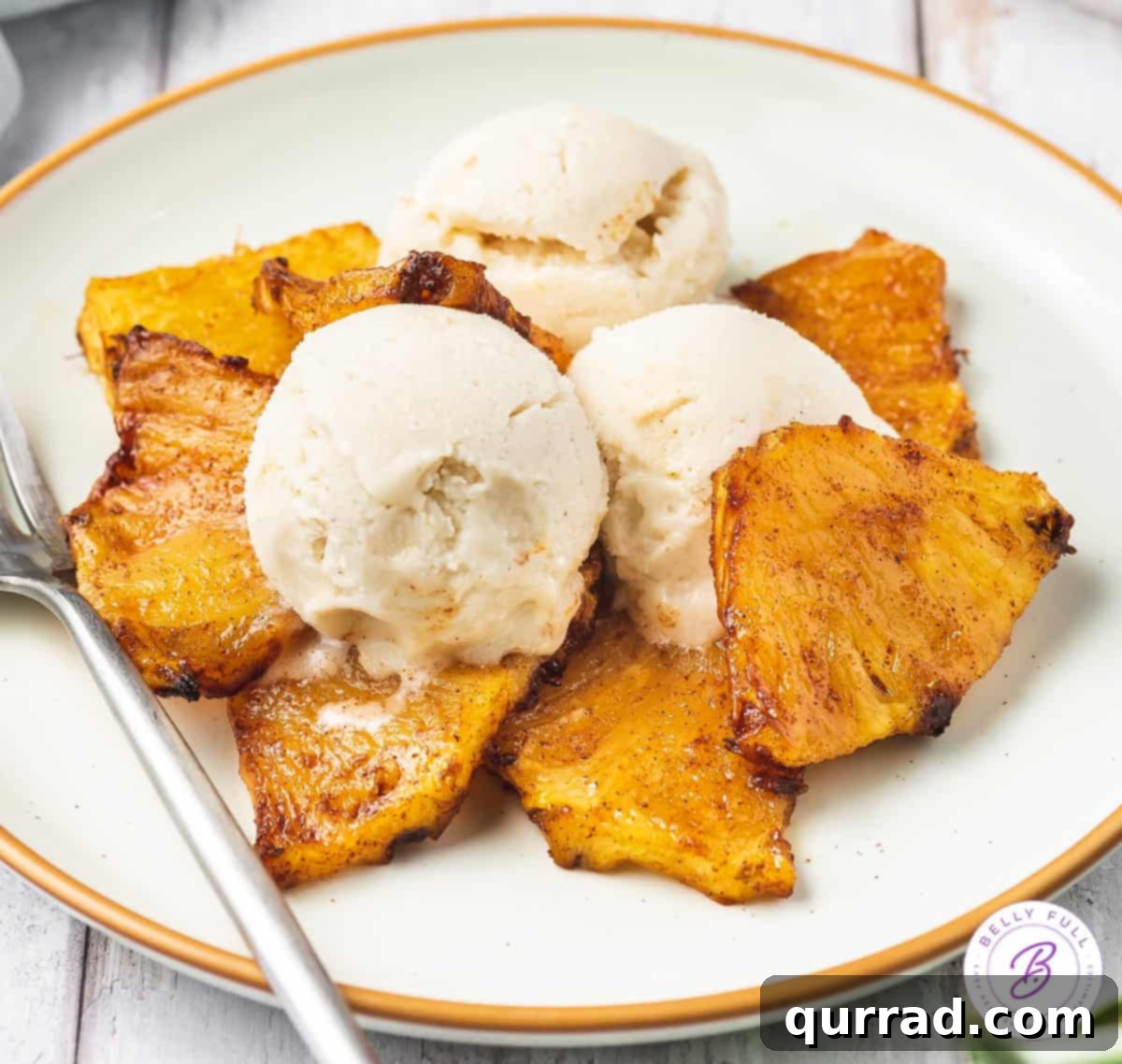 Caramelized Air Fryer Pineapple 7 White plate with air fried pineapple pieces and vanilla ice cream.