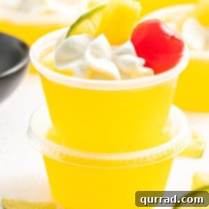 stack of two mai tai jello shots garnished with whipped cream and a cherry