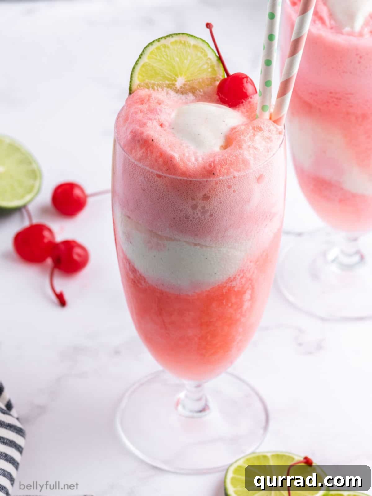 ice cream float with maraschino cherries and a lime wedge, in a tall glass